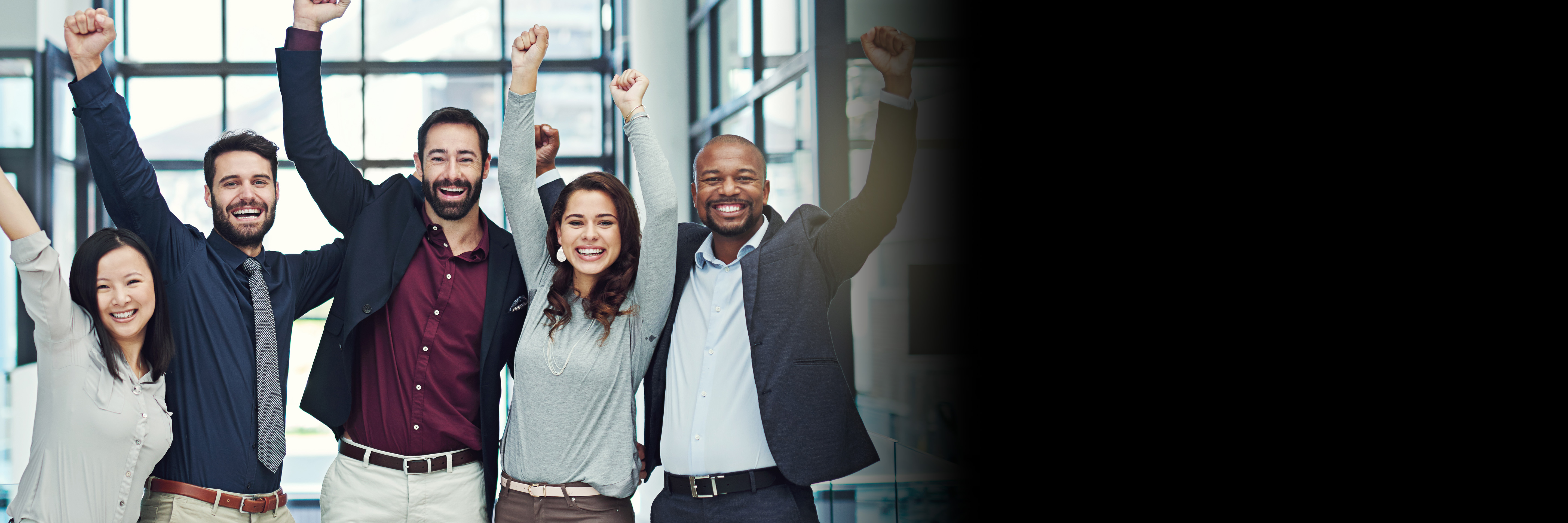 Five professionals standing together raising their arms to cheer 