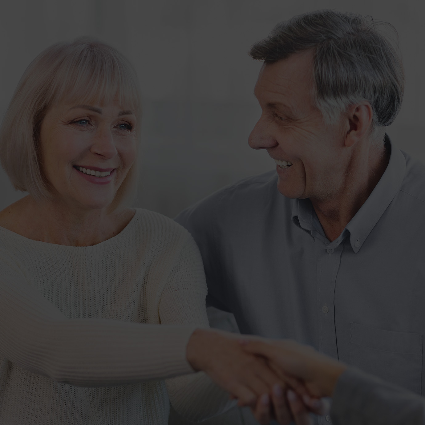 A lady hugged by a man is shaking hand with another lady