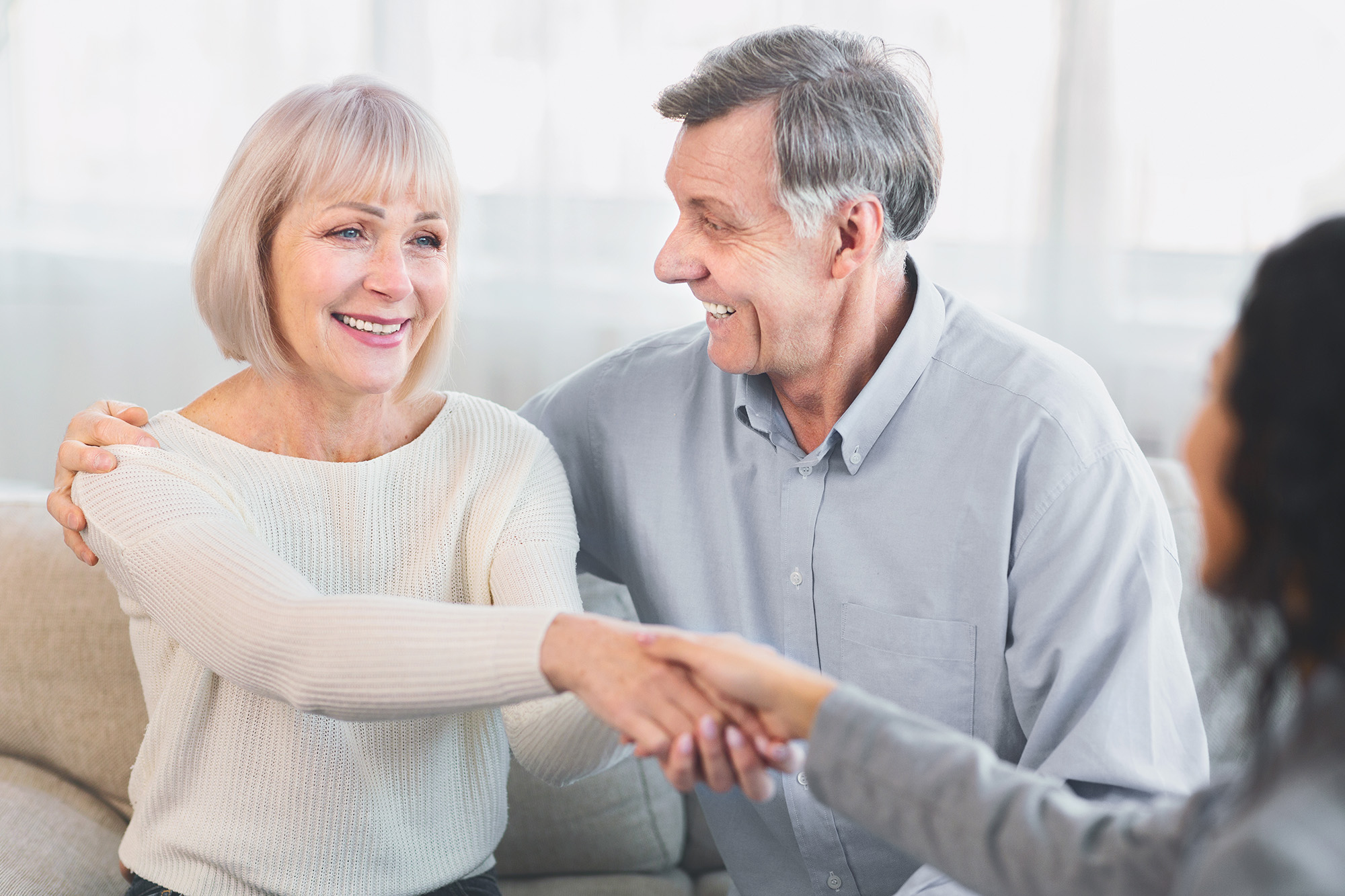 A lady shaking hand with an agent with her hudband beside her