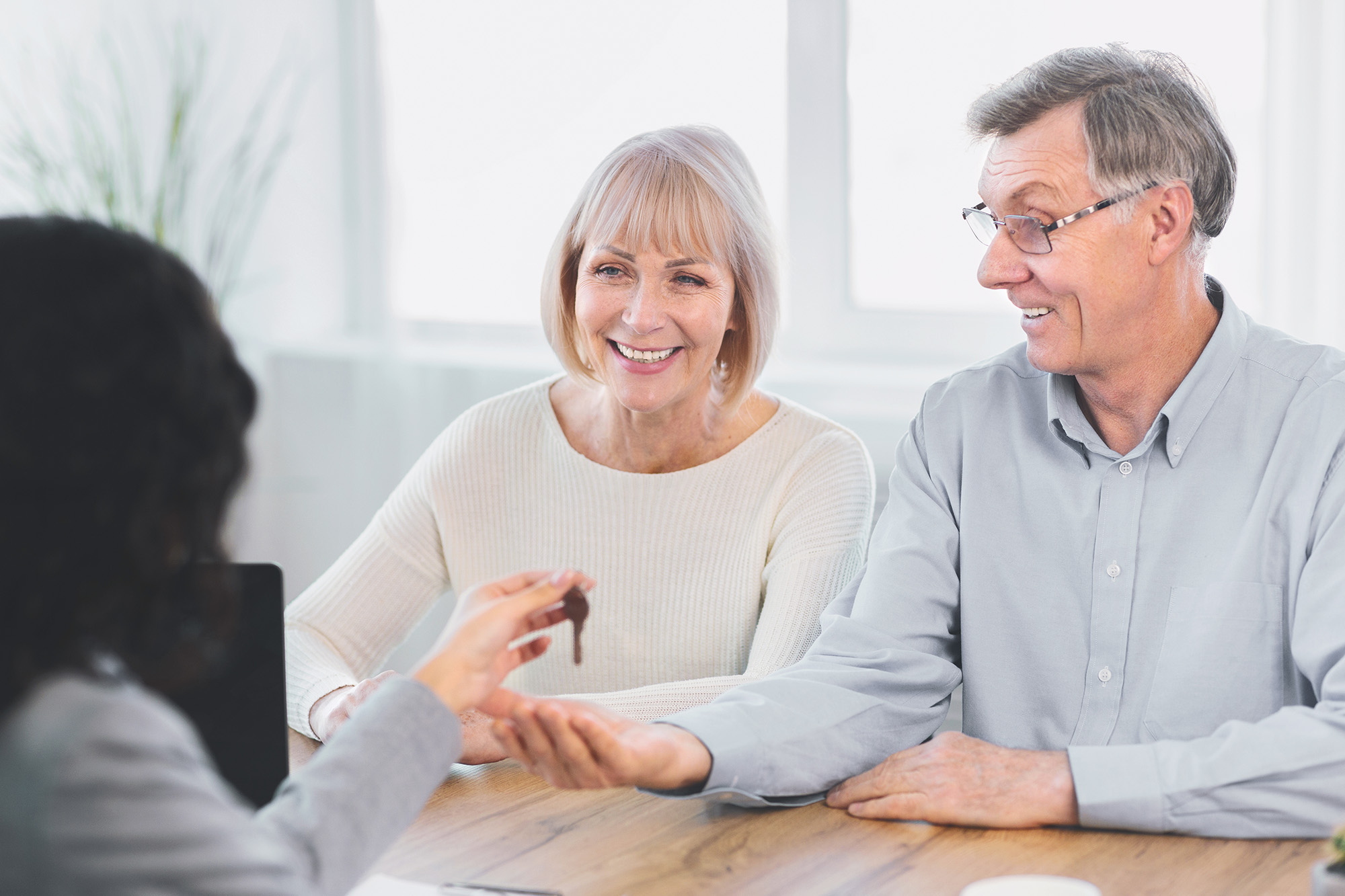 A senior couple handed a house key from a female agent