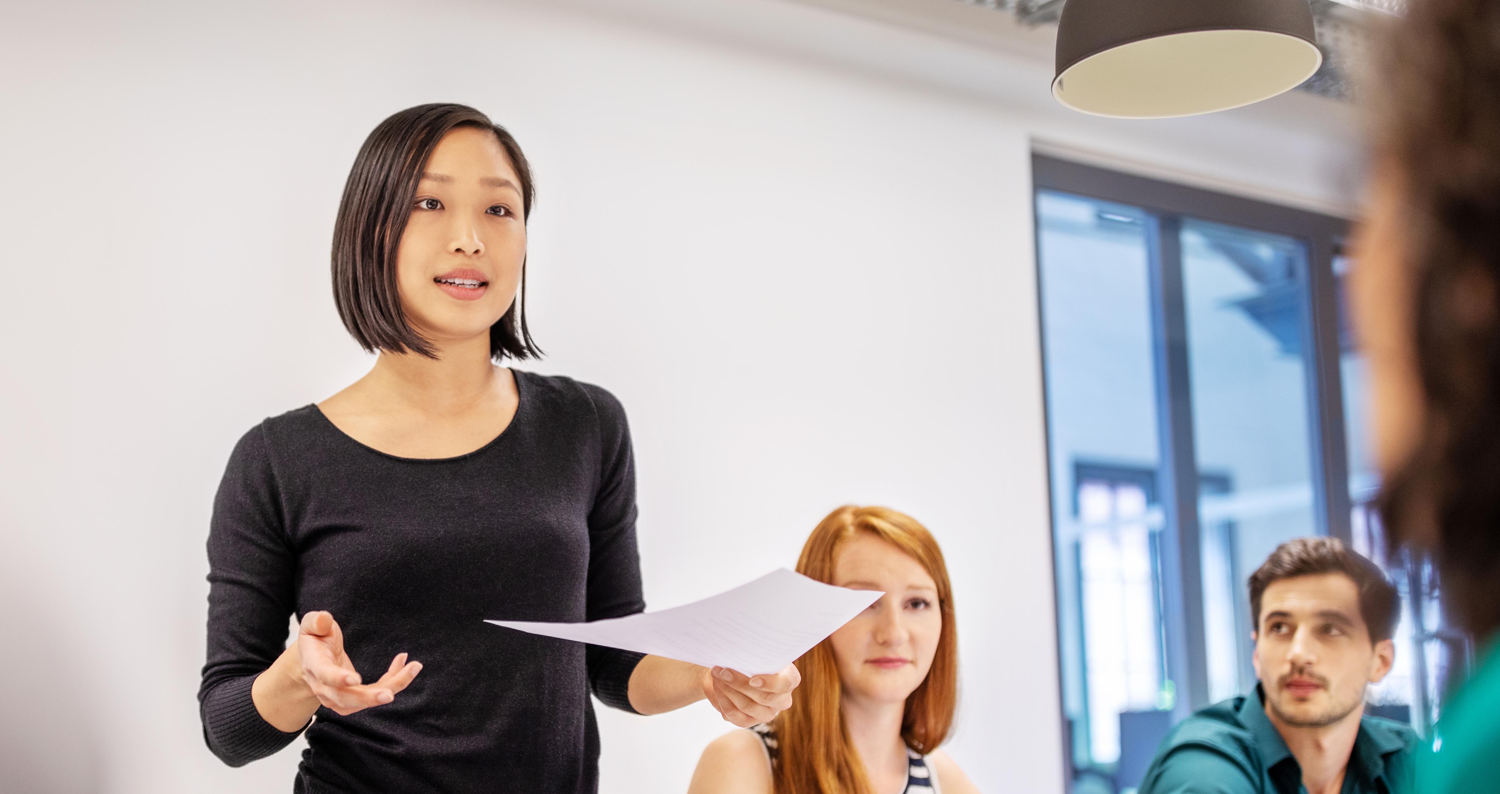 A woman giving speech in a business meeting with paper in her hand