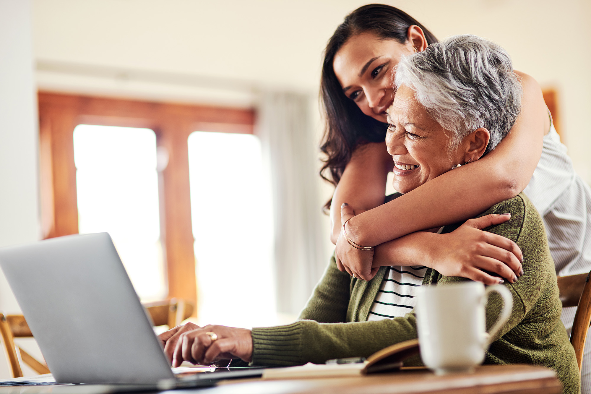 Daughter hugging her mom in front of a laptop