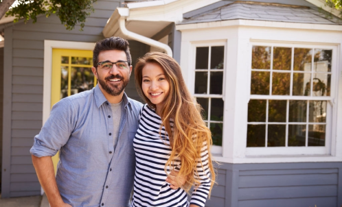 A yound couple standing in front of a house