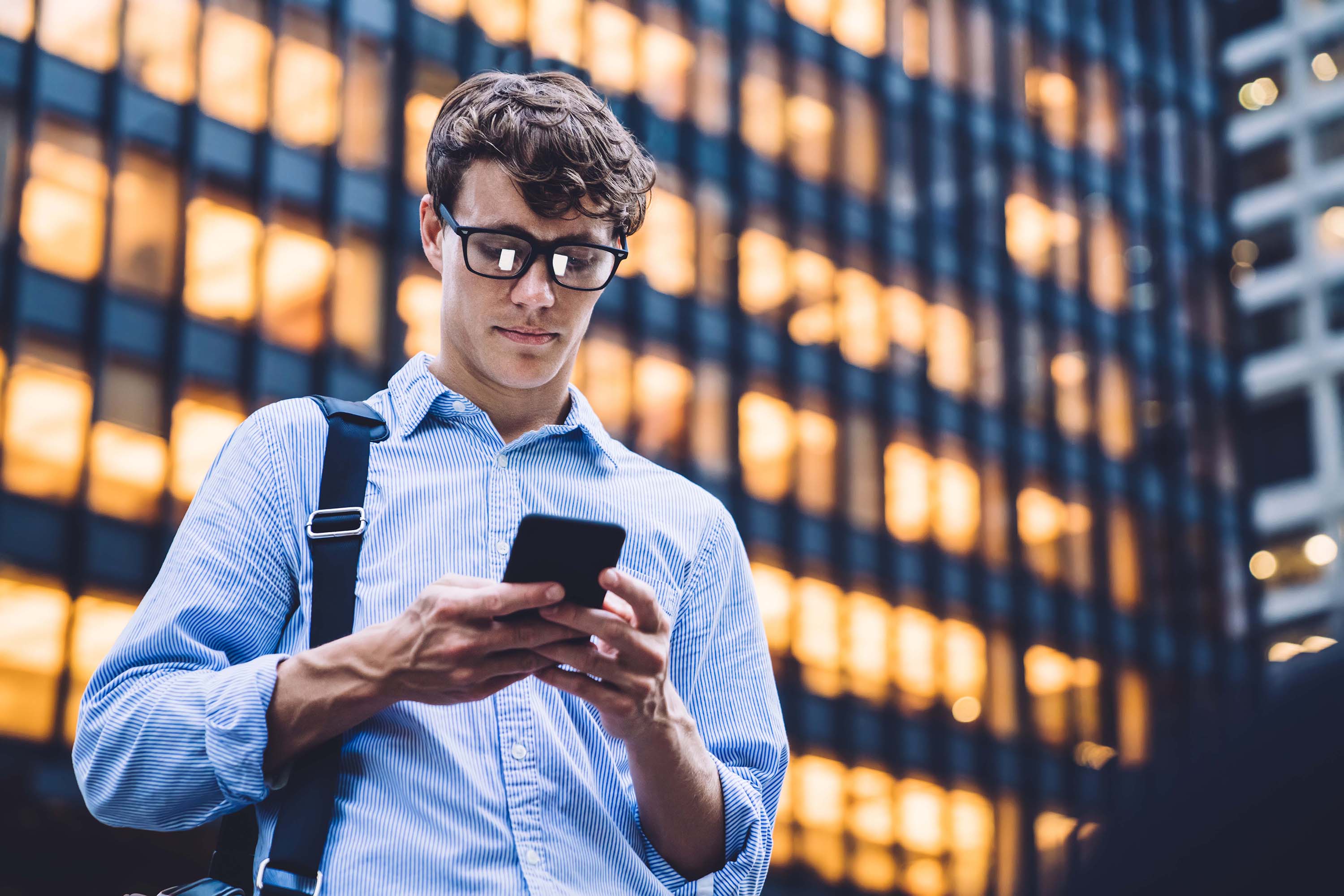 A man using a phone in front of a building