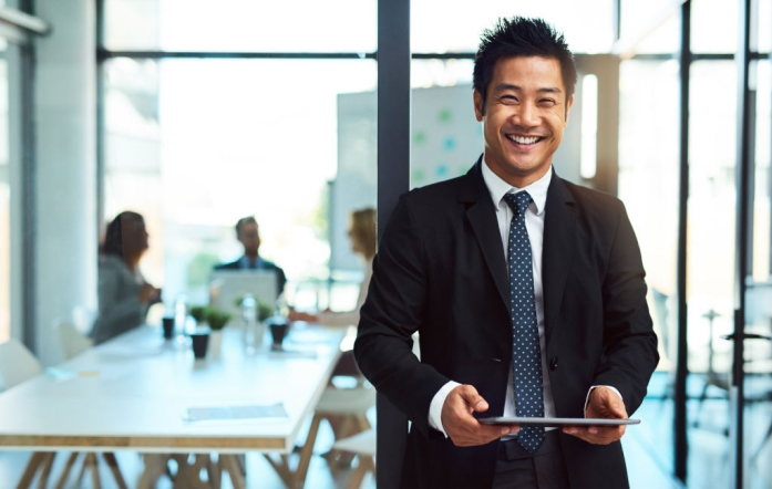 A man holding a tablet smiling at in an office