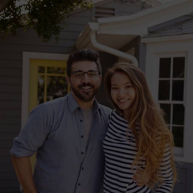 A young couple standing in front of a house