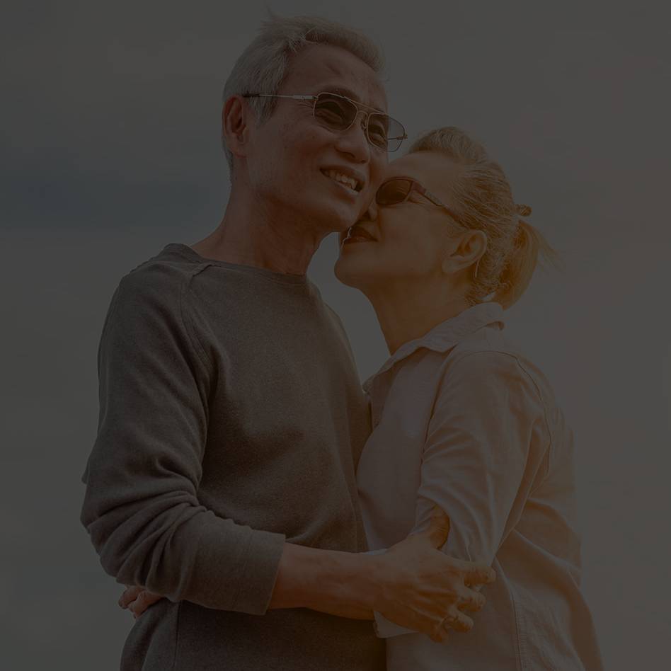 An old couple holiding each other on the beach