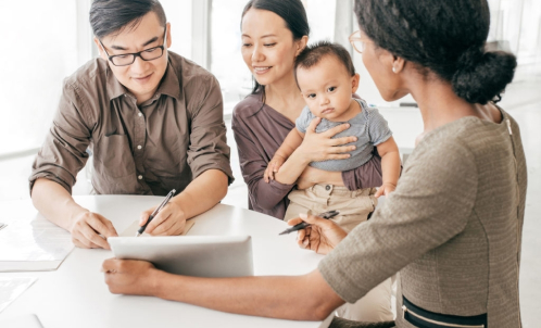 A young family sitting together talking to an agent who's holding a tablet