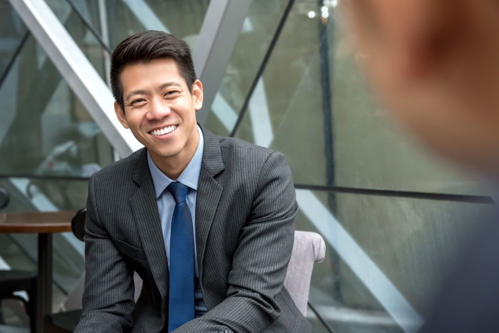 A business man sitting on an outdoor chair smiling