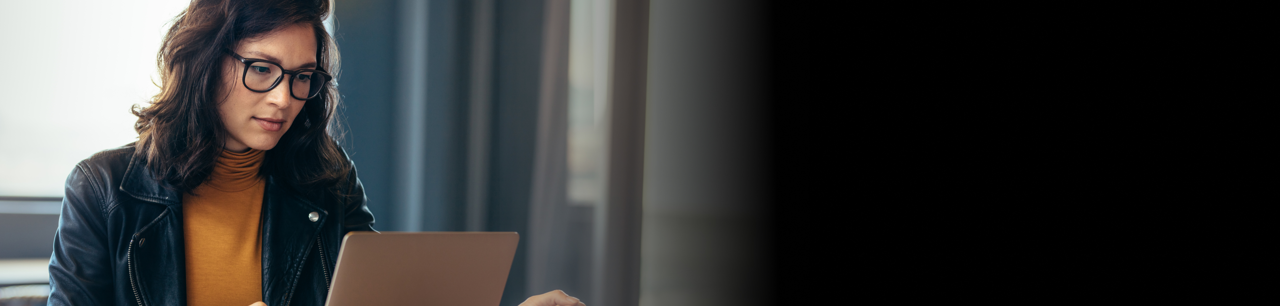 A woman sitting by a laptop looking at the screen