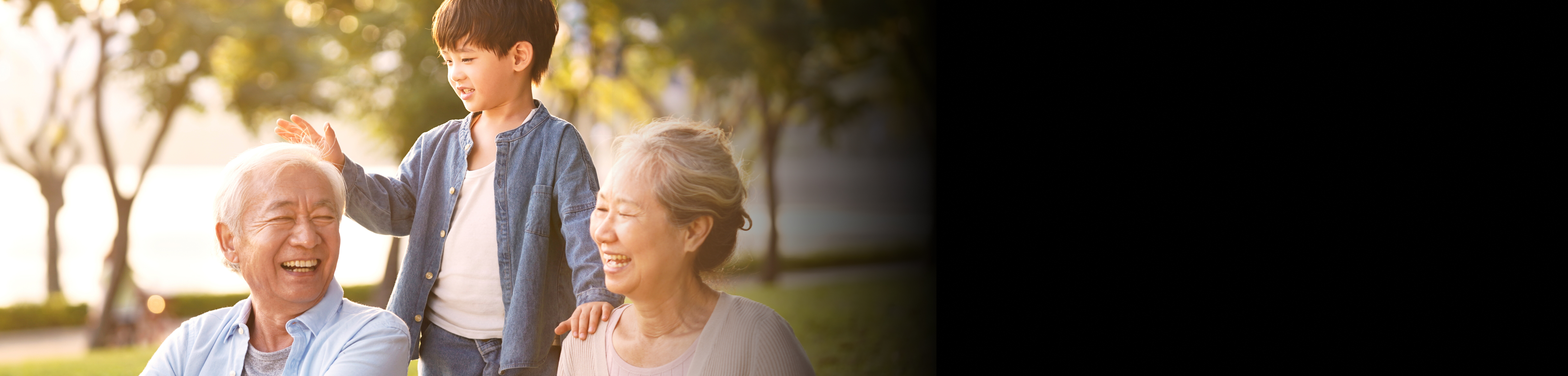 A senior couple playing with their grandson in a park by the lake