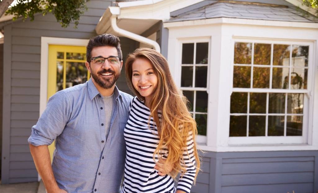 A young couple standing in front of a house