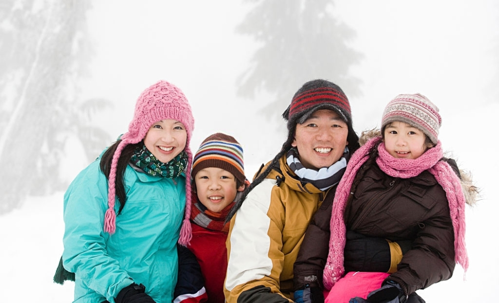 Parents and their two young kids hiking in winter forest 