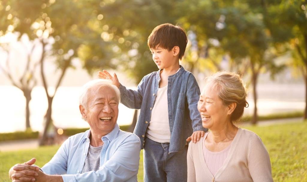 A senior couple playing with their grandson in a park by the lake