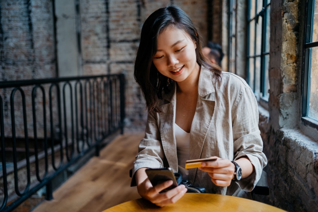 A young lady holding a credit card and a mobile phone