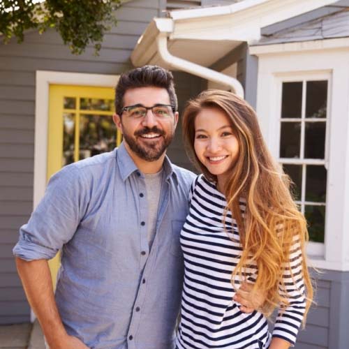 A young couple standing in front of a house